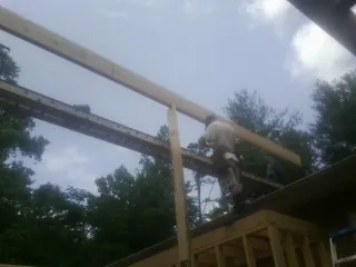 Carpenter setting a ridge beam over a new addition frame — Ice Dam Removal by Roofing Brothers in Orange Beach