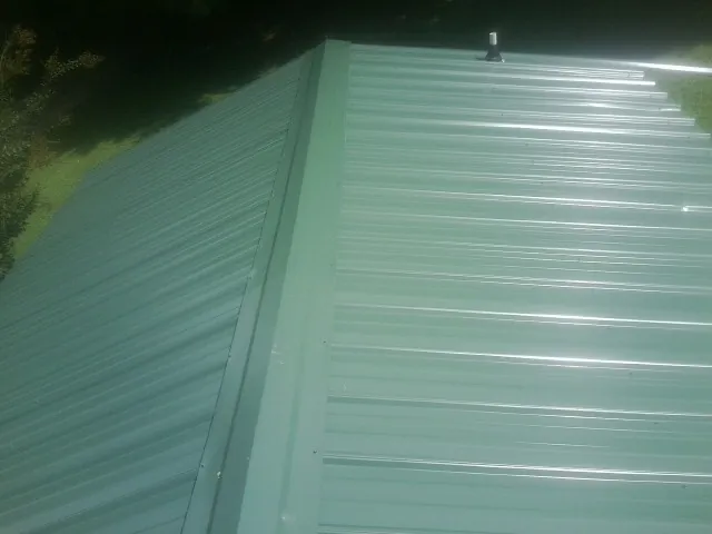 New green metal panels meeting at the ridge of a roof — Flat Roof Repair work by our crew in Orange Beach