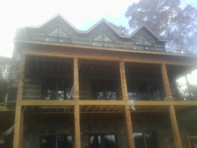 Dormers and porch framing on a large log home under construction — Roof Coating work by our crew in Orange Beach