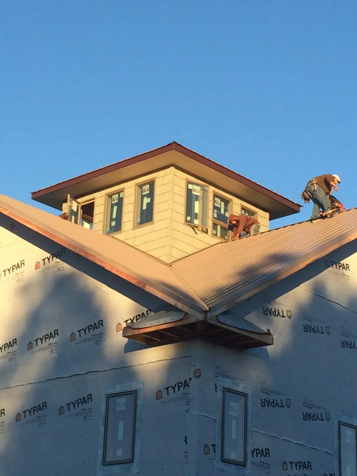 Roofers working around a rooftop cupola on a new metal roof at sunset — Roof Waterproofing in Orange Beach by Roofing Brothers
